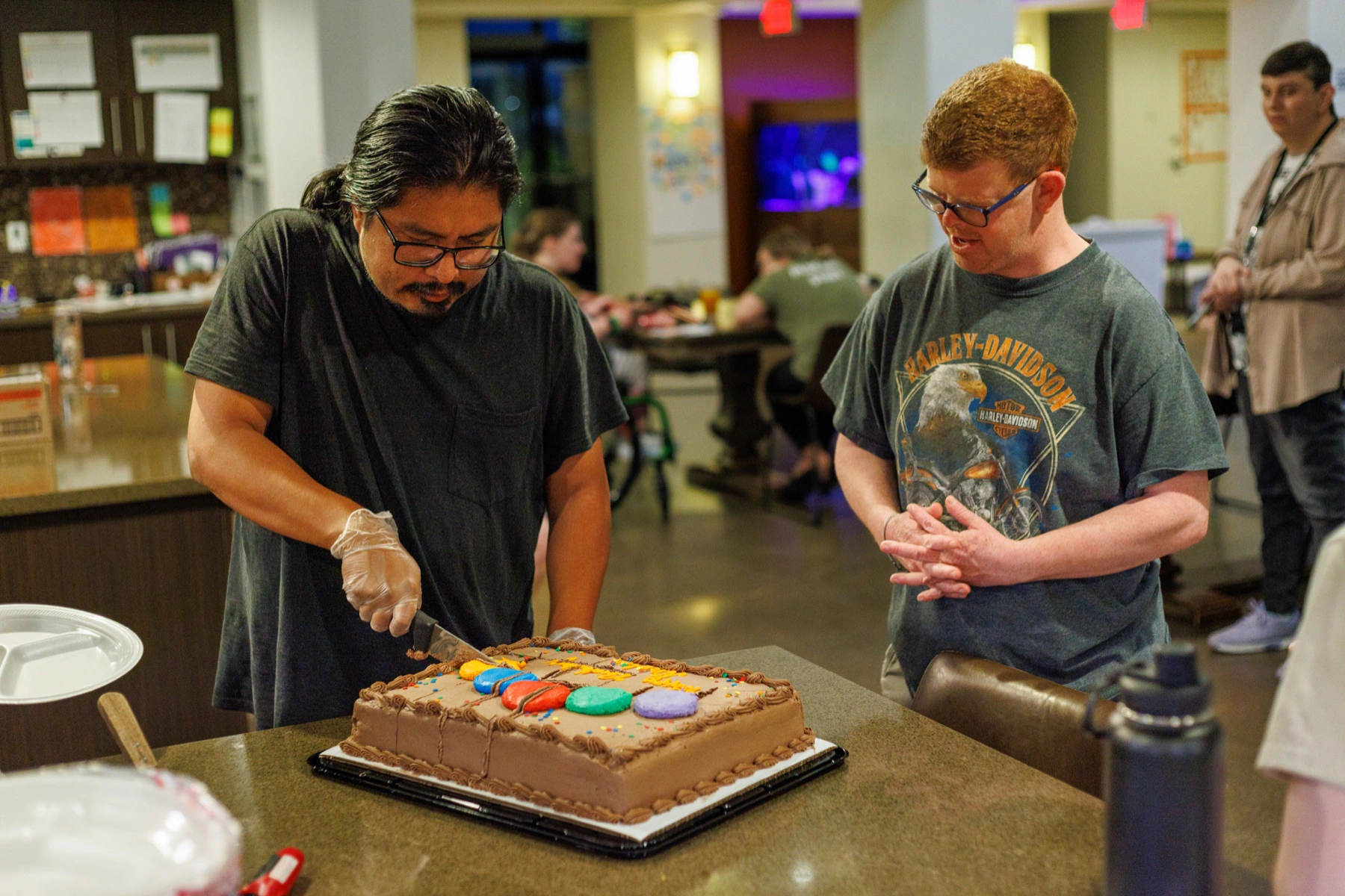 A resident and staff member decorating a cake in the community kitchen